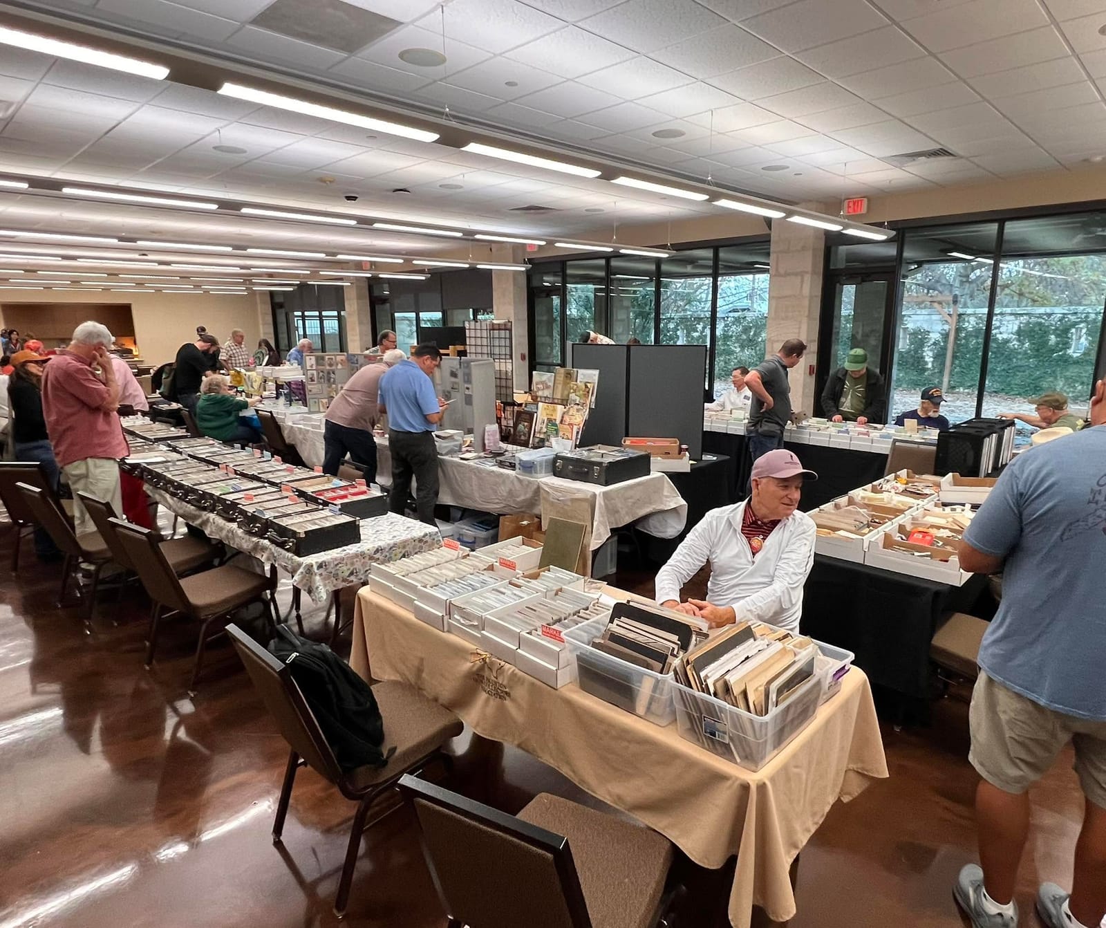 Wide view of the DFW Paper Show floor with long rows of dealer tables full of postcard boxes.