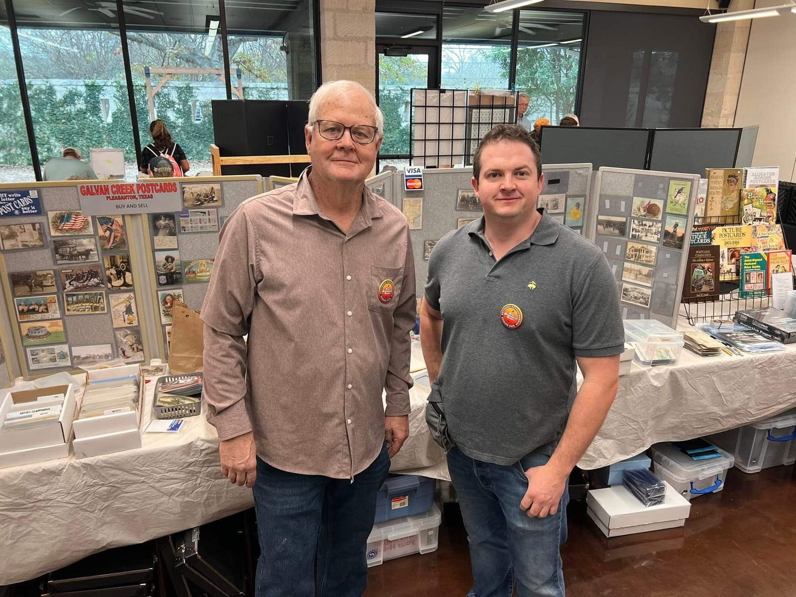 Two dealers standing in front of the Galvan Creek Postcards booth at the DFW Paper Show.